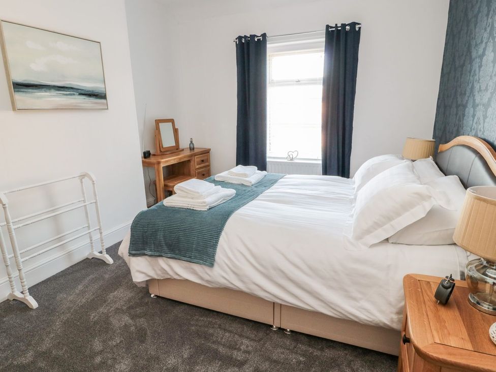 A bedroom with a bed and bedside table at 23 Northumbria Terrace in Amble