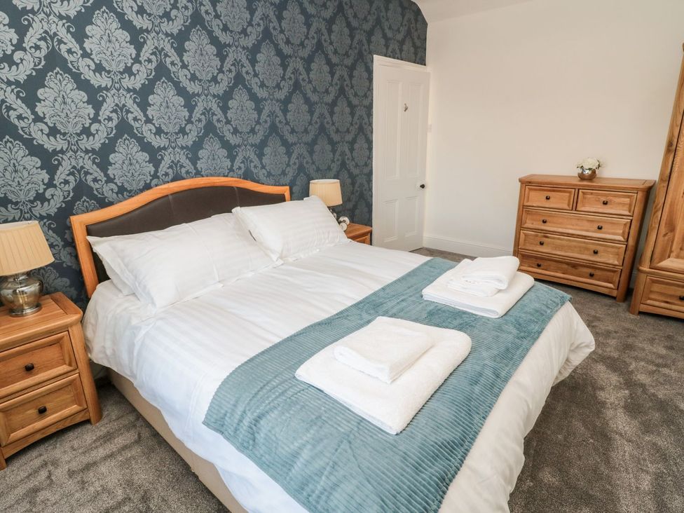 A bedroom with a bed and wooden furniture at 23 Northumbria Terrace in Amble