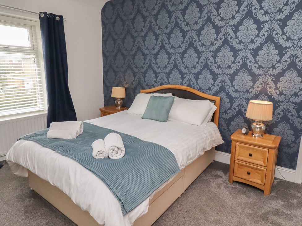 A bedroom with a double bed and bedside table at 23 Northumbria Terrace in Amble