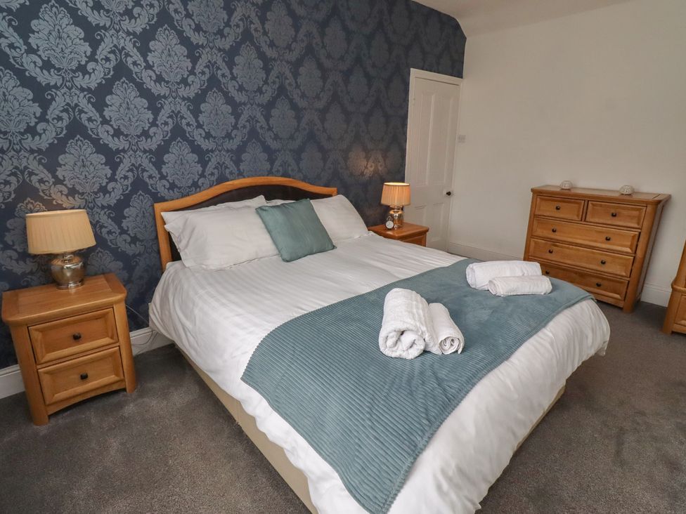 A bedroom with a bed and bedside tables at 23 Northumbria Terrace Amble