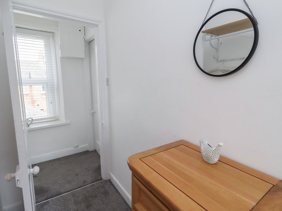 A hallway with a mirror and a wooden drawer at 23 Northumbria Terrace in Amble