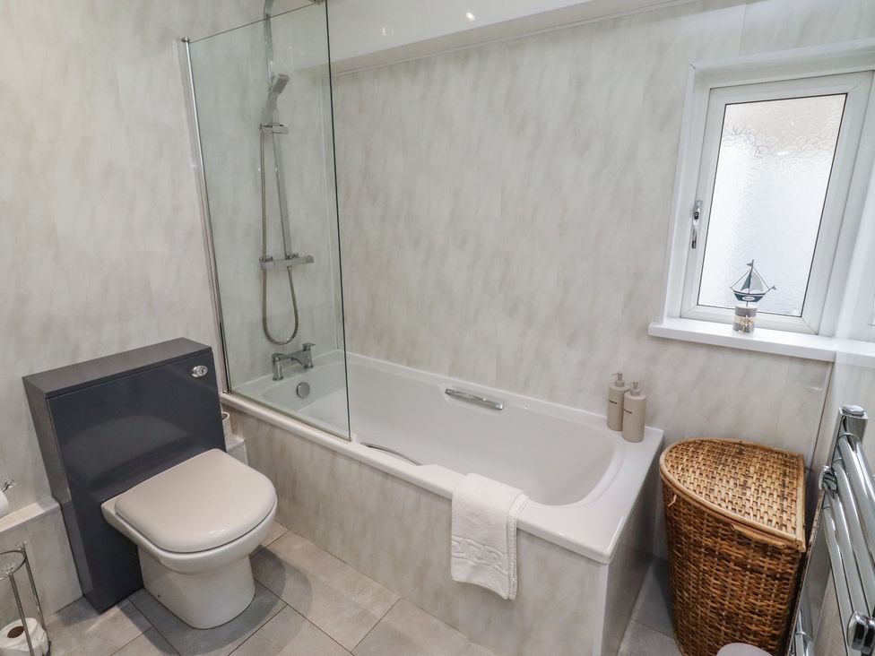 A bathroom with a bathtub and shower at 23 Northumbria Terrace in Amble