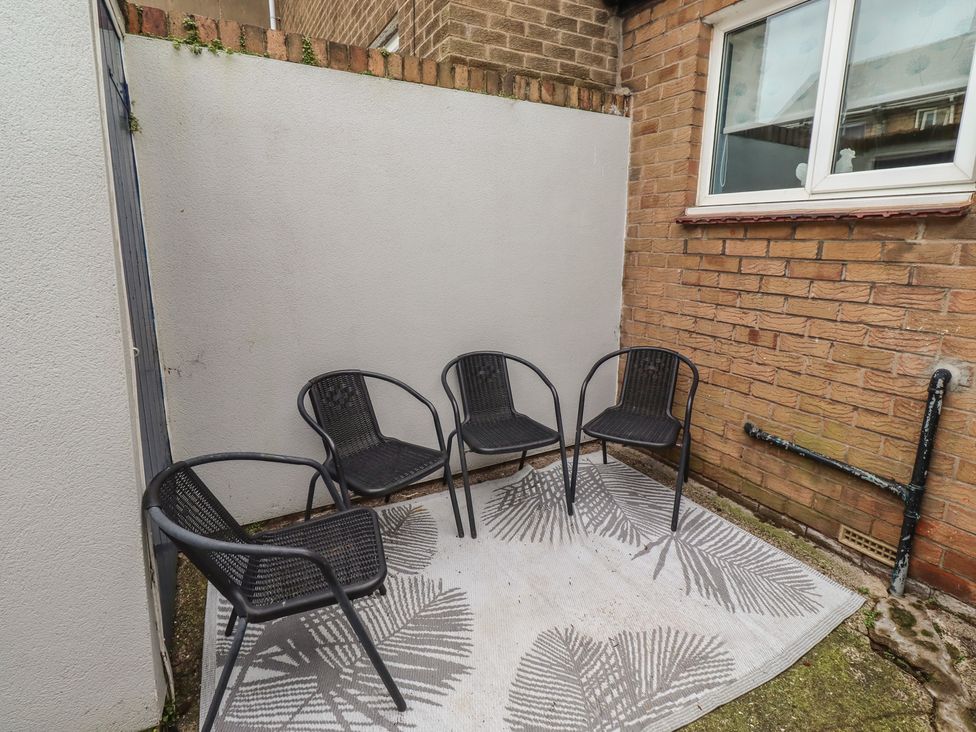 An outdoor seating area with four chairs and a rug at 23 Northumbria Terrace Amble