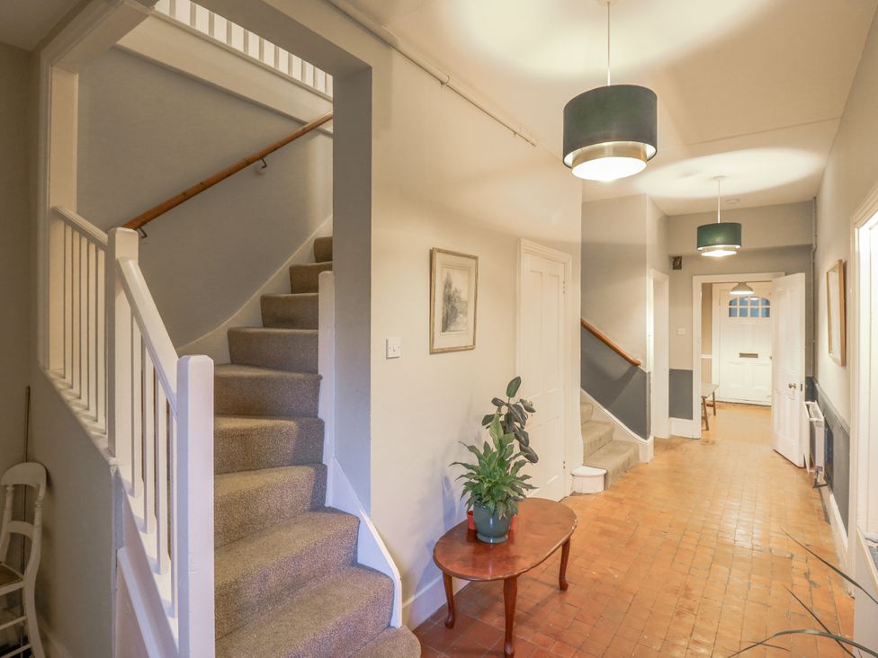 A hallway with a staircase and a table with a plant at The Farmhouse in Whitchurch, Buckinghamshire