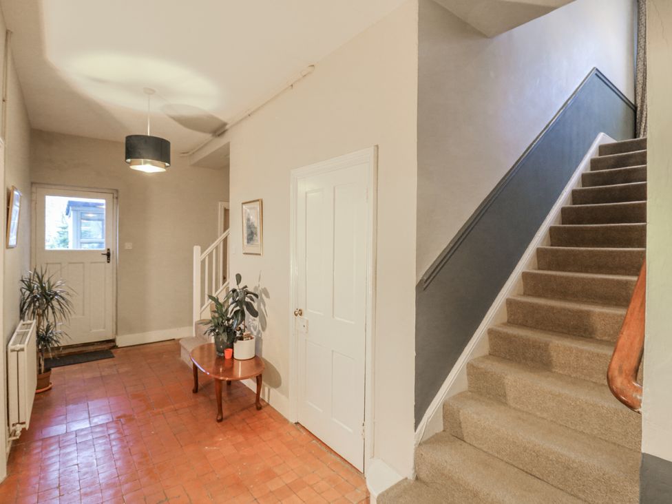 A hallway with a staircase and a table at The Farmhouse in Whitchurch, Buckinghamshire