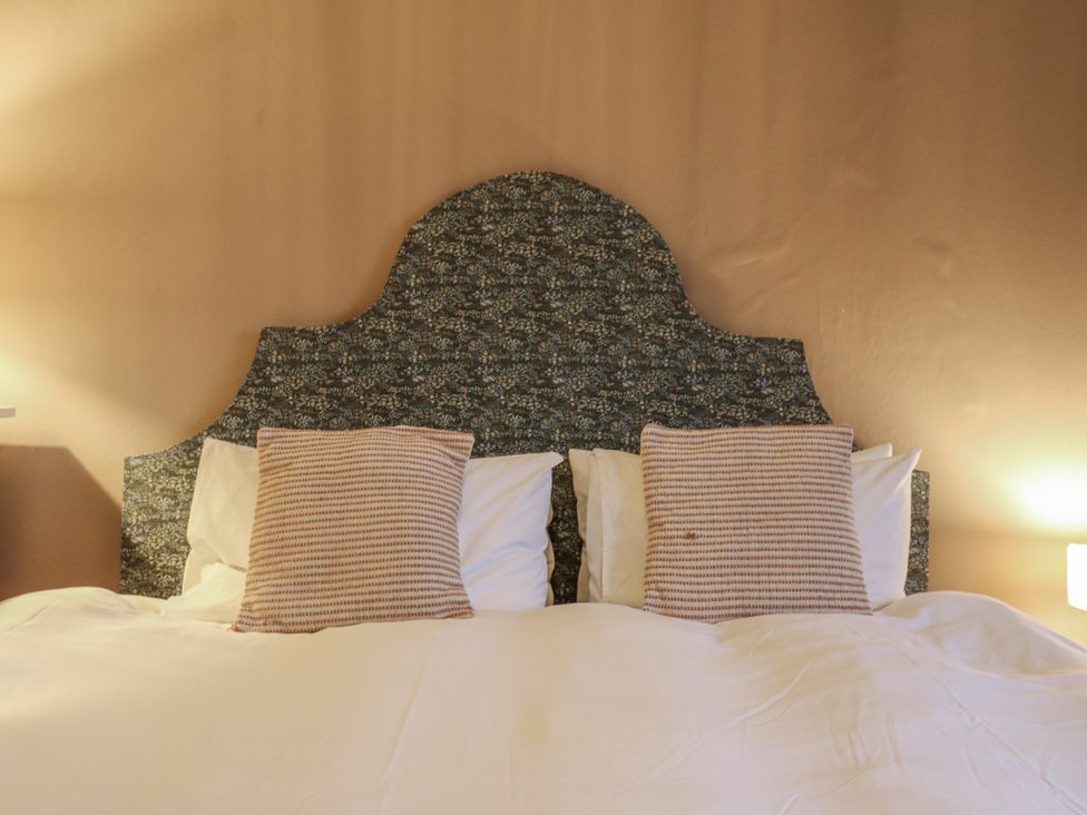 A bed with striped and plain pillows at The Farmhouse in Whitchurch, Buckinghamshire