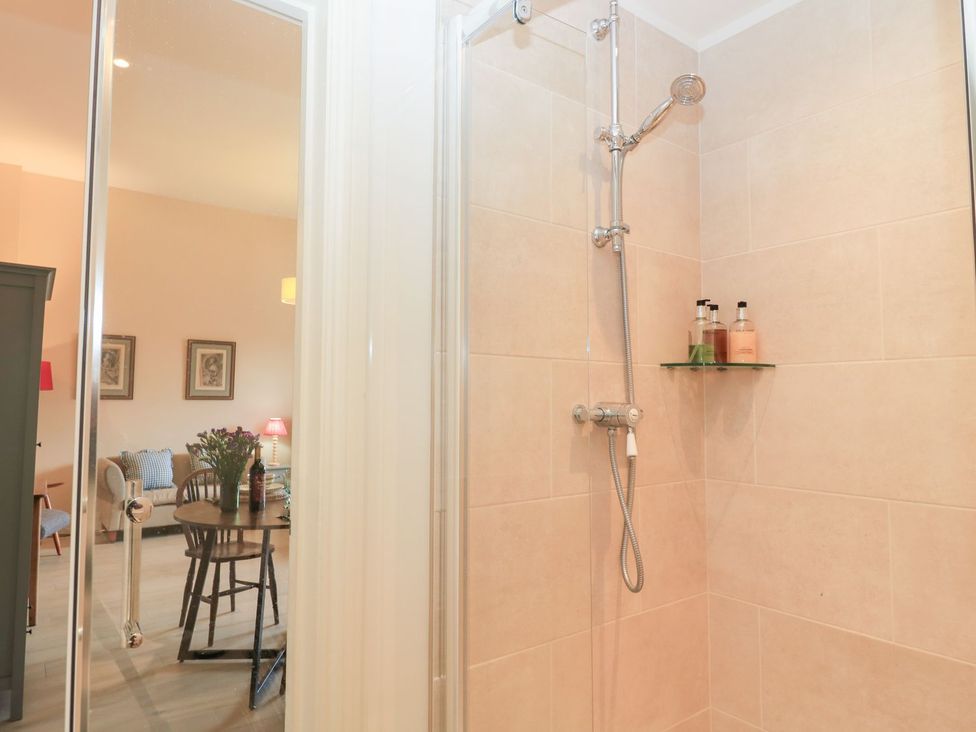 A shower with a glass door and shelves at Woodcock Studio Andoversford near Cheltenham