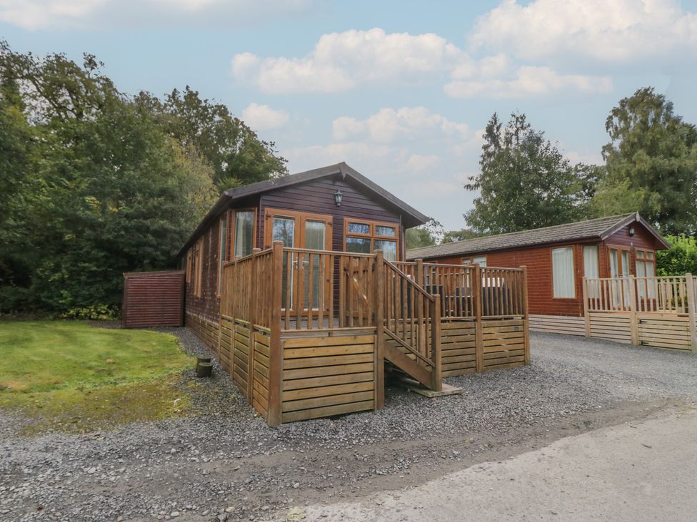 A wooden cabin with a deck and garden area at 32 Grasmere in Windermere