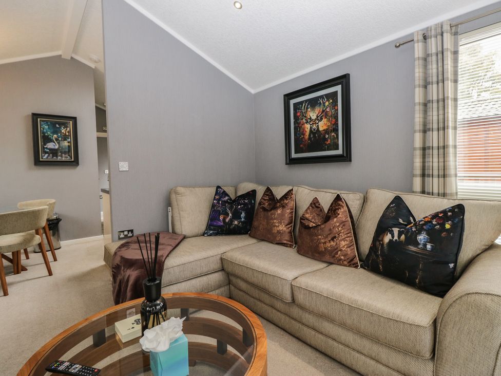 A living room with a sofa, table, and paintings at 32 Grasmere, White Cross Bay near Windermere