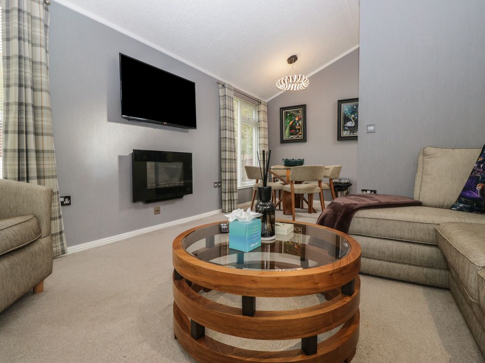 A living room with a sofa, coffee table, and television at 32 Grasmere, White Cross Bay near Windermere