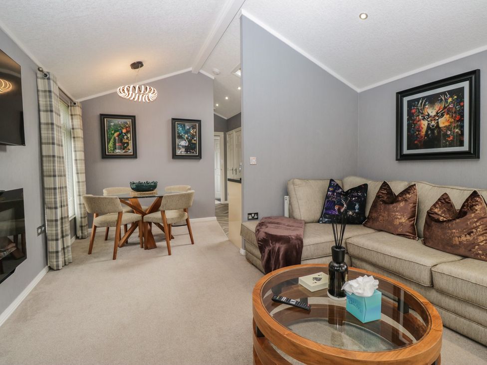 A living room with a sofa and dining table at 32 Grasmere, White Cross Bay near Windermere