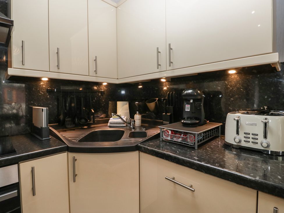 A kitchen with cabinets, sink, coffee maker, and toaster at 32 Grasmere, White Cross Bay near Windermere
