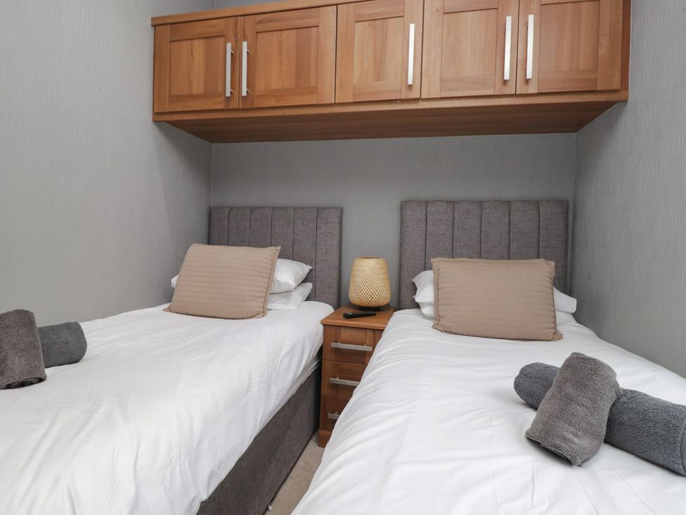 A bedroom with two single beds and a bedside table at 32 Grasmere, White Cross Bay near Windermere