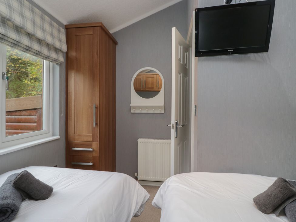 A bedroom with two beds and a wardrobe at 32 Grasmere, White Cross Bay near Windermere