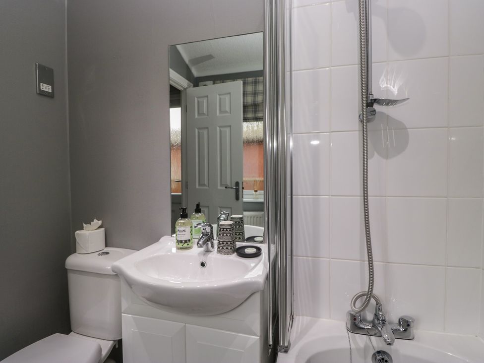 A bathroom with a toilet, wash basin, and shower at 32 Grasmere, White Cross Bay near Windermere