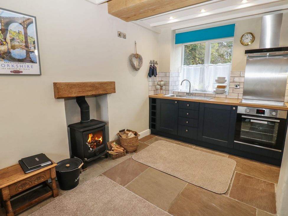 A kitchen with a wood stove and wooden countertop at Tyg Cottage in Ripon