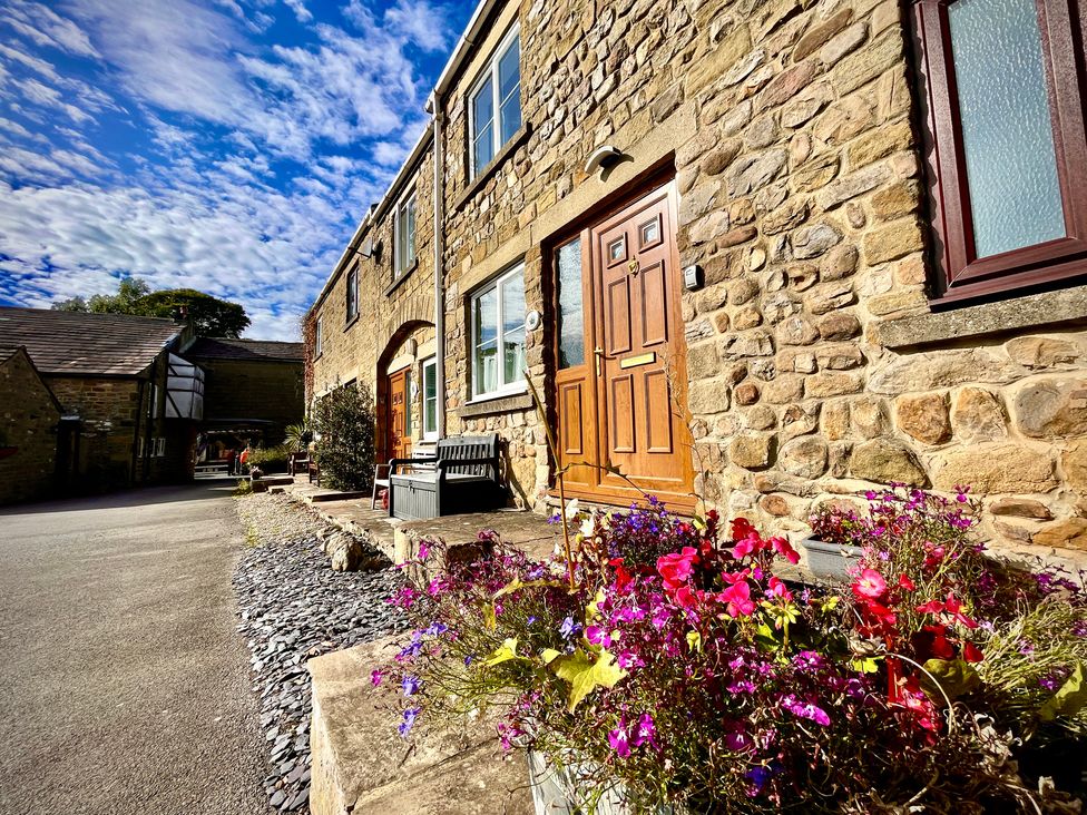 An outdoor area with stone building and flowers in pots at Tyg Cottage Masham
