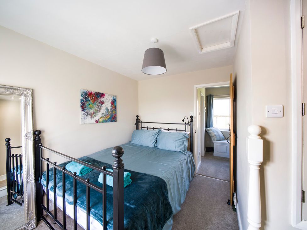 A bedroom with a bed and mirror at Tyg Cottage in Masham
