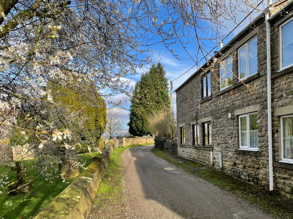 An outdoor view of a road beside a stone house at Tyg Cottage in Masham