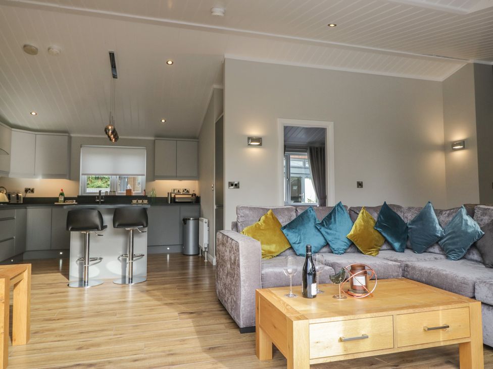 A living room with a sofa and kitchen area at 7 Lake View in Windermere