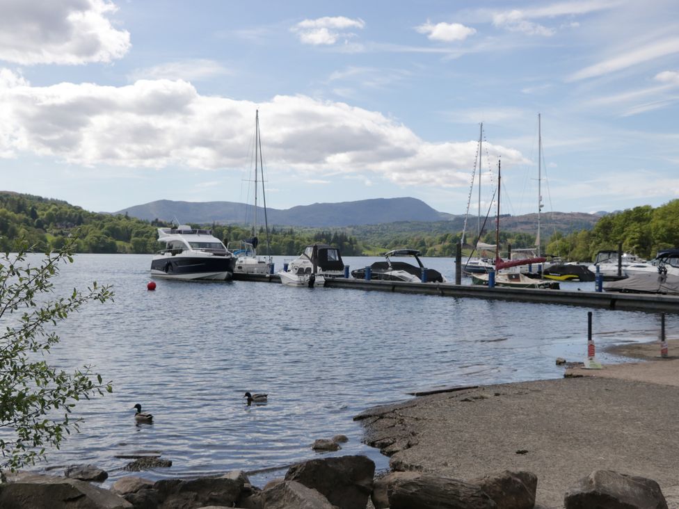 A view of boats at a dock on a lake with mountains in the background at 7 Lake View in Windermere