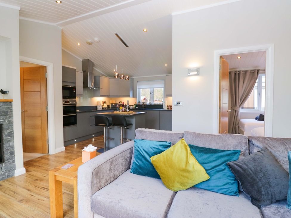 A living room with a sofa and kitchen area at 7 Lake View, Lake View 7, White Cross Bay near Windermere