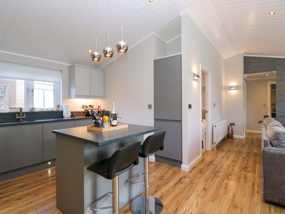 A kitchen with bar stools and countertop at 7 Lake View, White Cross Bay near Windermere