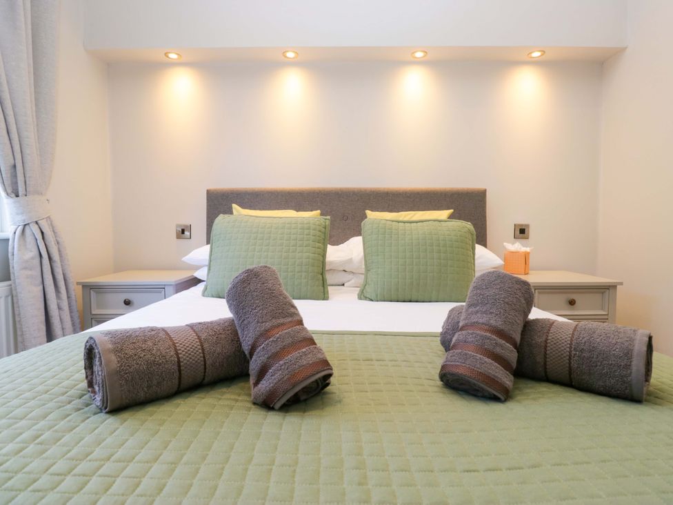 A bedroom with a bed and towels arranged on a green bedspread at 7 Lake View, Lake View 7, White Cross Bay near Windermere