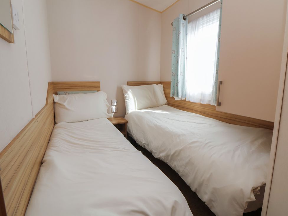 A bedroom with two single beds and a window at E10 Static Caravan in Rhyl