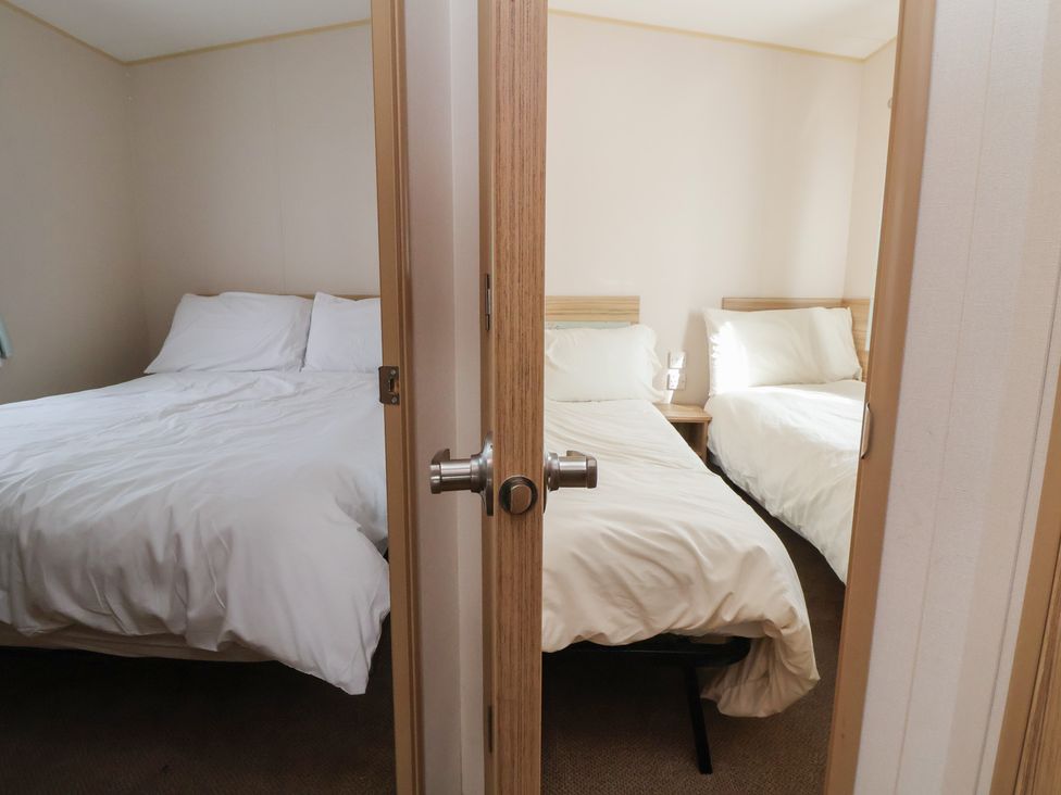 A bedroom with two beds and a bedside table at E10 Static Caravan in Rhyl