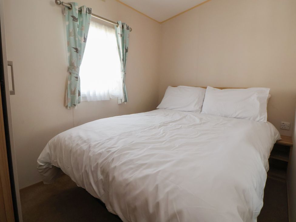 A bedroom with a bed and curtains at E10 Static Caravan Rhyl