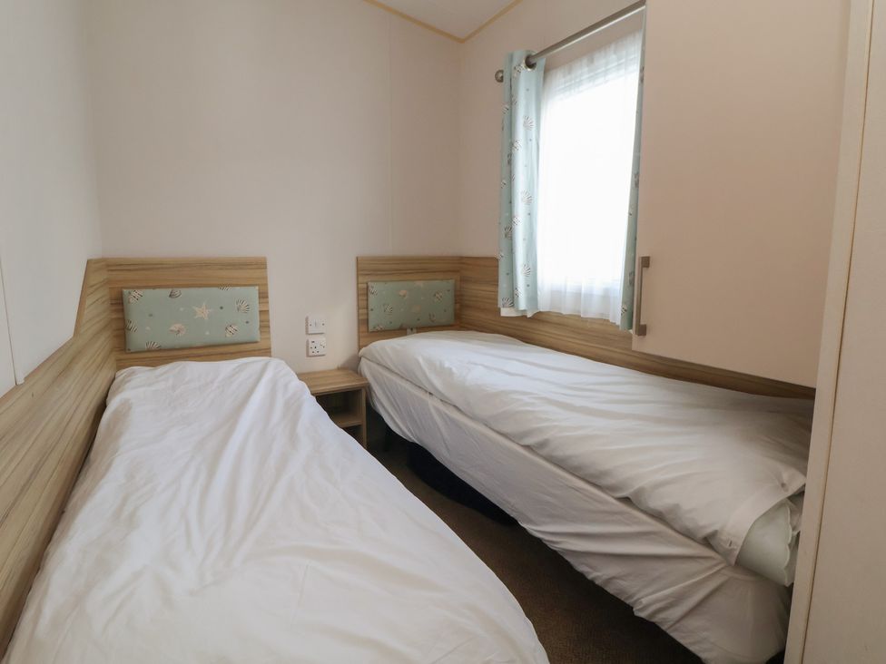 A bedroom with two single beds and a window at A5 Static Caravan Rhyl