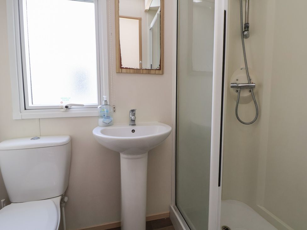 A bathroom with a toilet, sink, and shower at A5 Static Caravan Rhyl