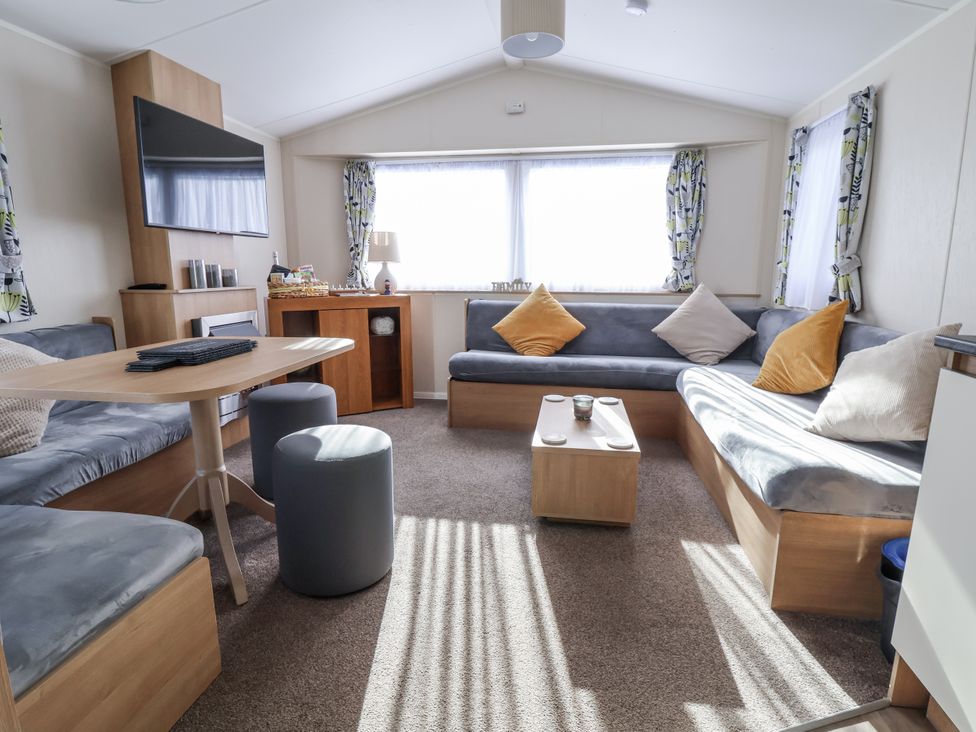A living room with a television and seating area at Chappie's Caravan - Rhyl