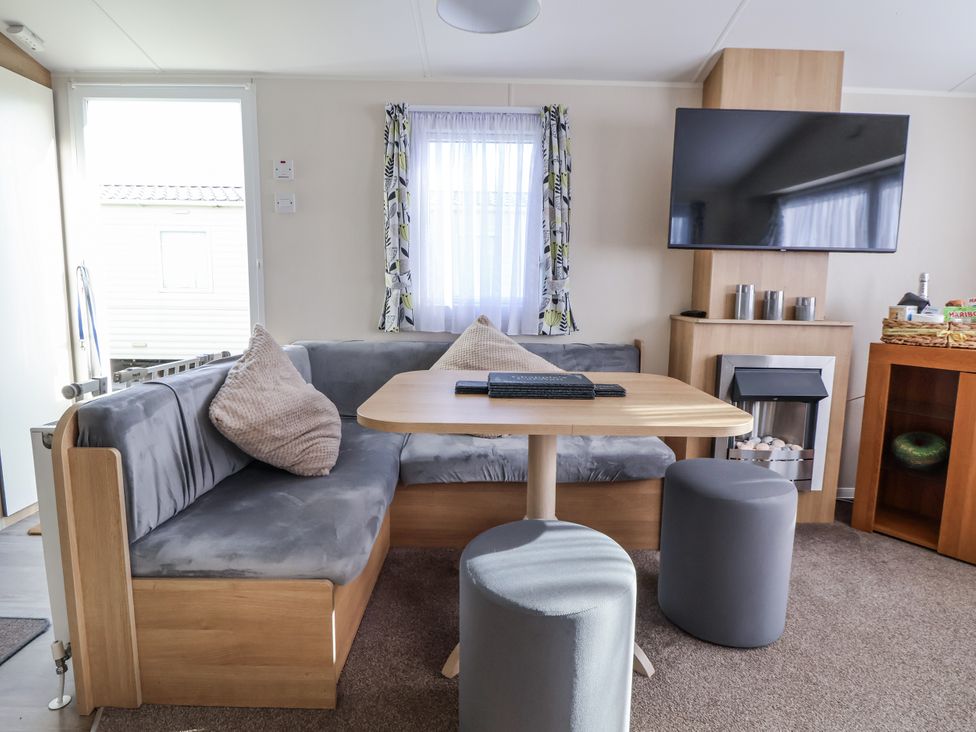 A snug with a sofa and table at Chappie's Caravan - Rhyl