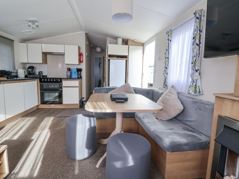 A living room and kitchen with a table and couch at Chappie's Caravan - Rhyl