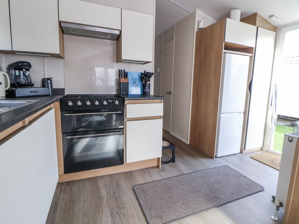 A kitchen with a stove and refrigerator at Chappie's Caravan - Rhyl