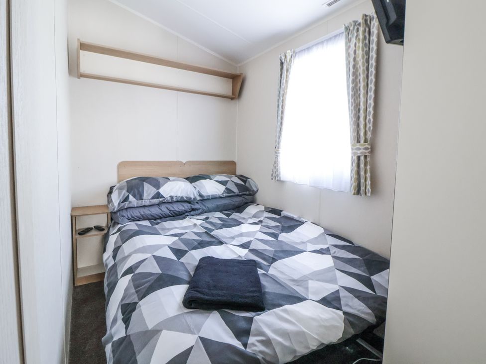 A bedroom with a bed and bedside table at Chappie's Caravan - Rhyl