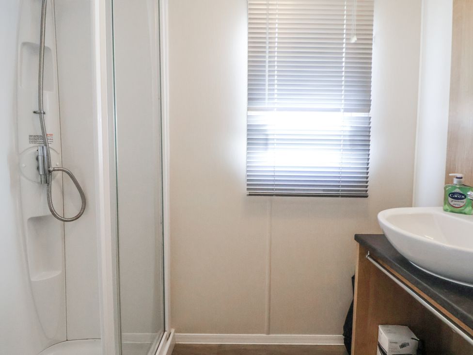 A bathroom with a shower and a sink at Chappie's Caravan - Rhyl