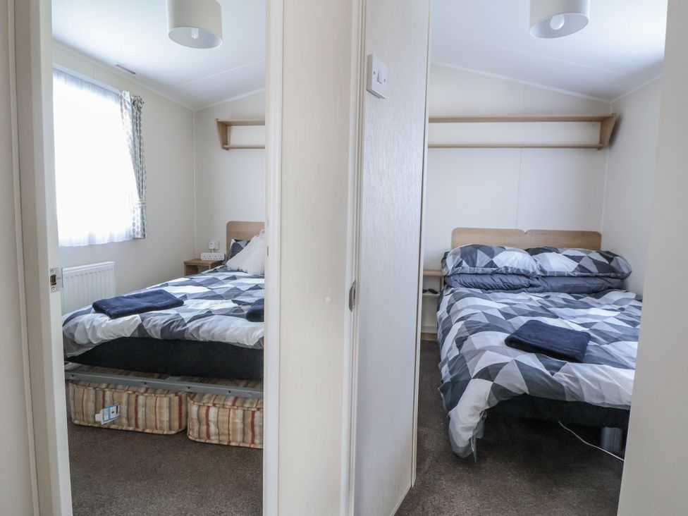 A bedroom with two beds and a window at Chappie's Caravan - Rhyl