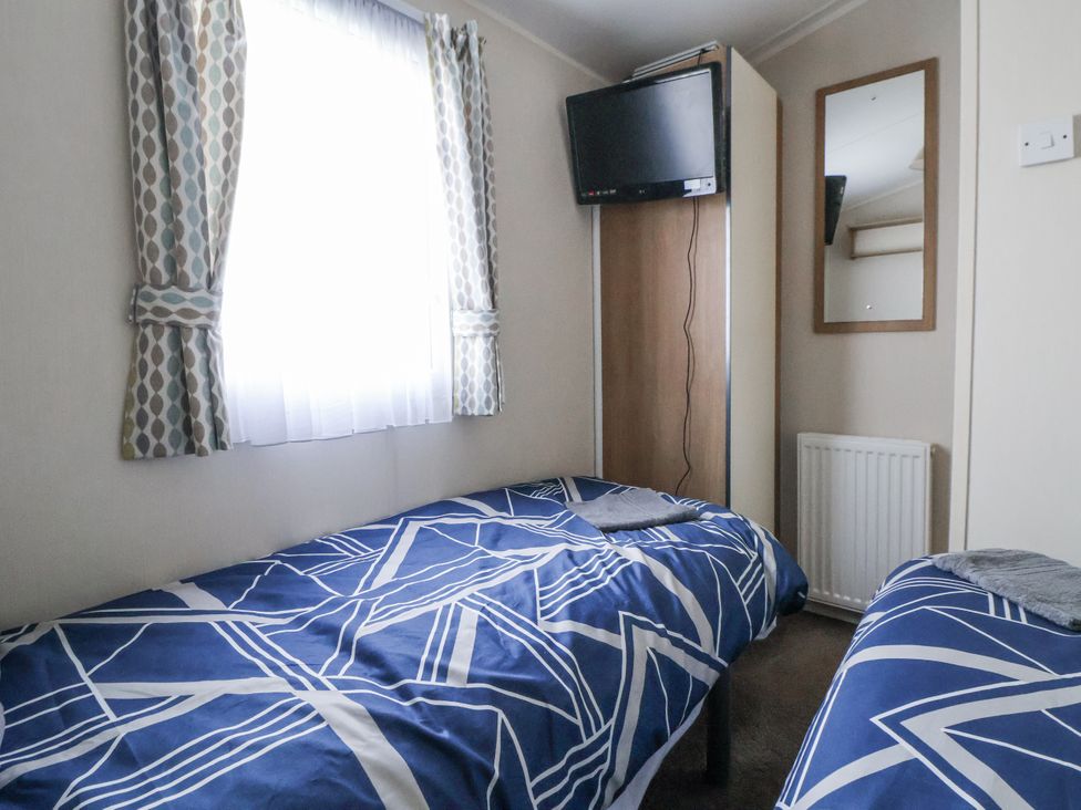 A bedroom with two beds and a television at Chappie's Caravan - Rhyl