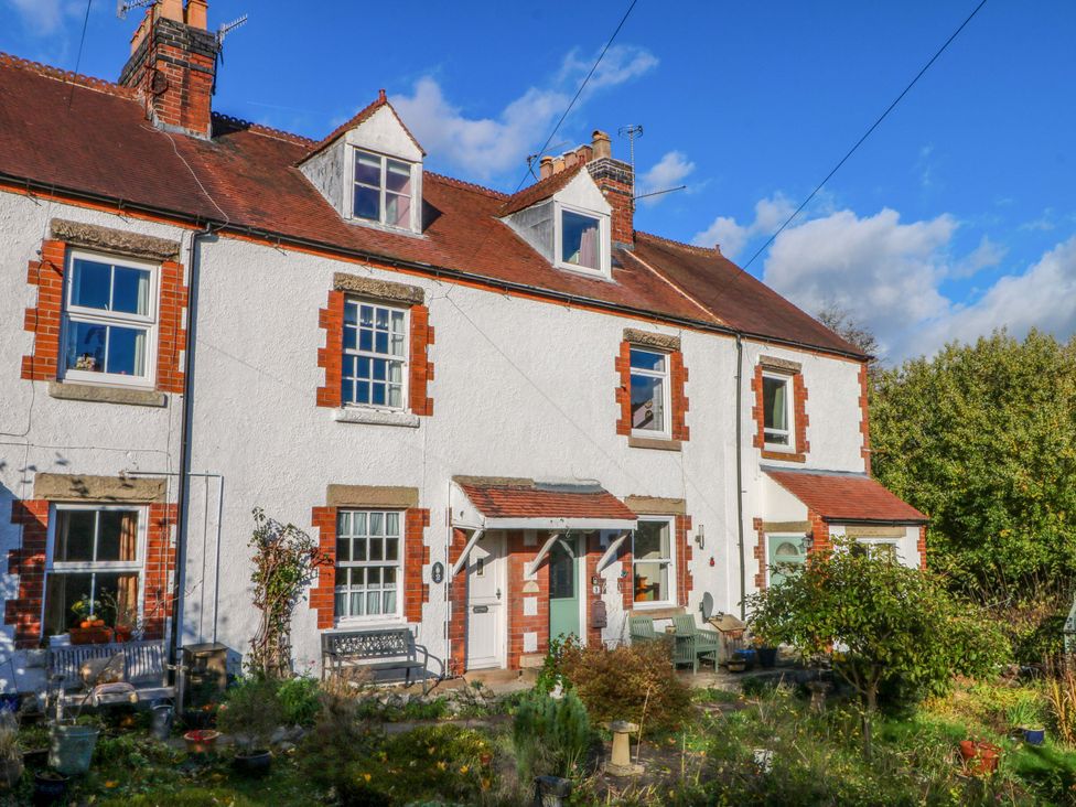 A house with garden and seating area at Pineapple Cottage in 