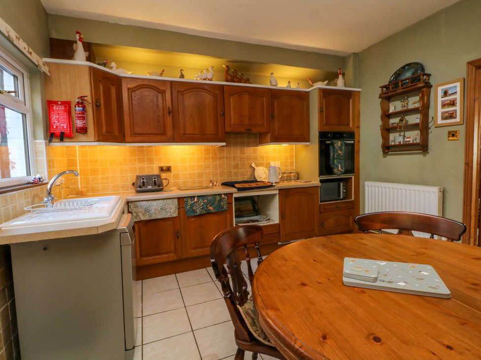 A kitchen with cabinets, sink, and table at Pineapple Cottage