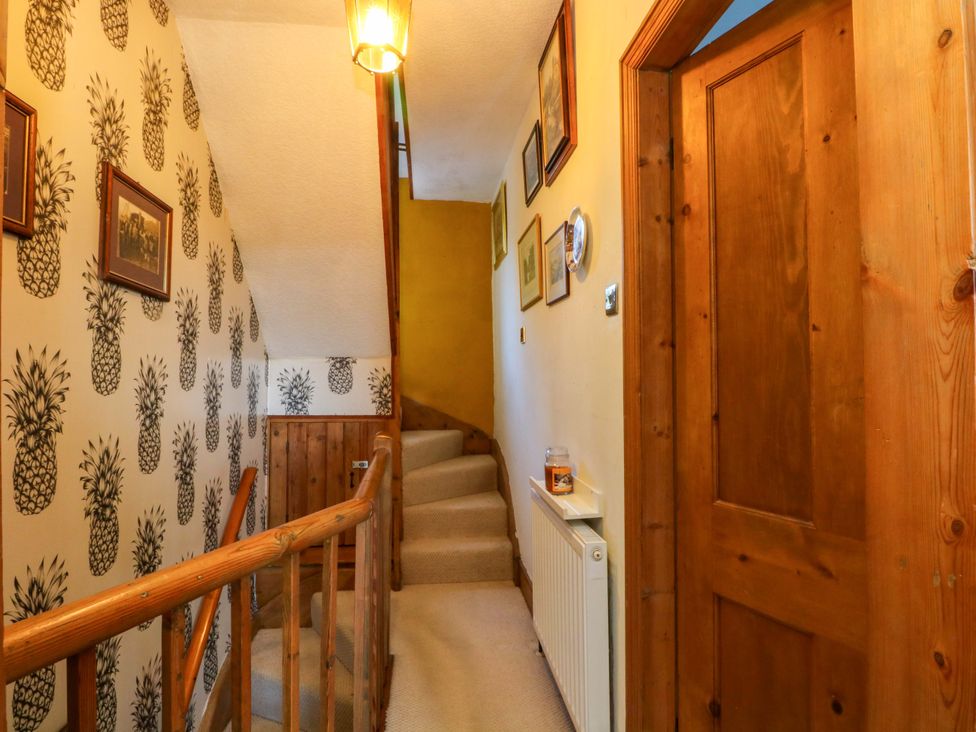 A hallway with a staircase and pictures on the wall at Pineapple Cottage