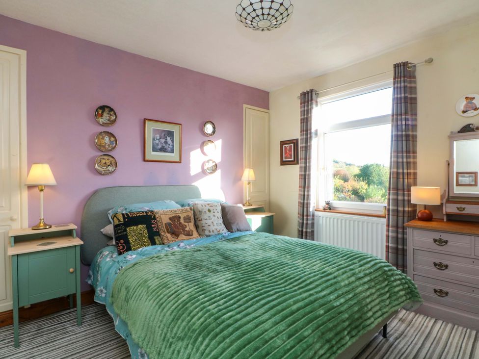 A bedroom with a bed and nightstand at Pineapple Cottage