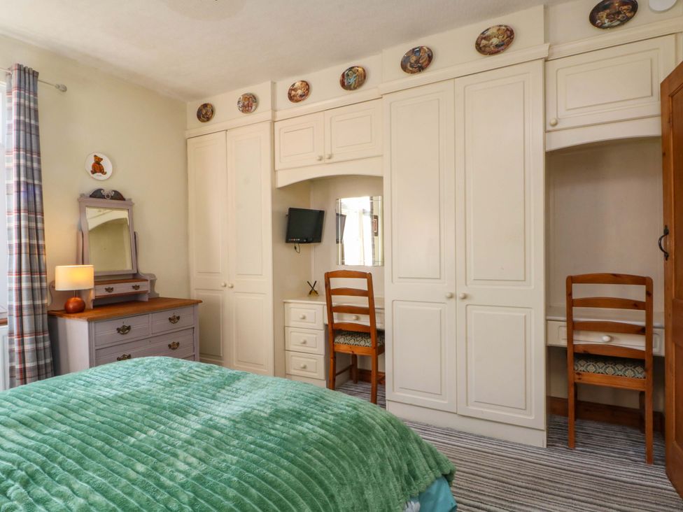 A bedroom with a bed and dressing table at Pineapple Cottage