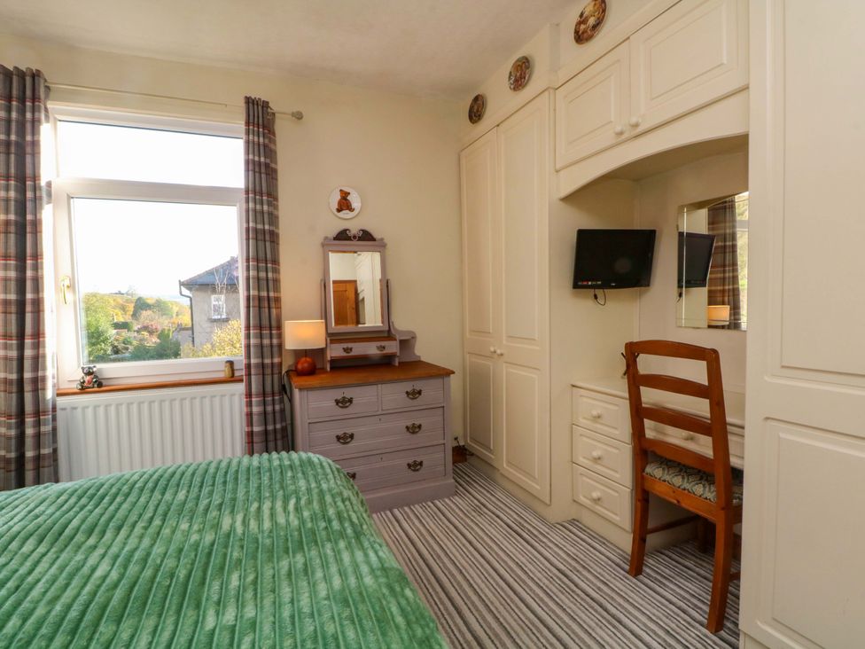 A bedroom with a bed, dresser, and TV at Pineapple Cottage