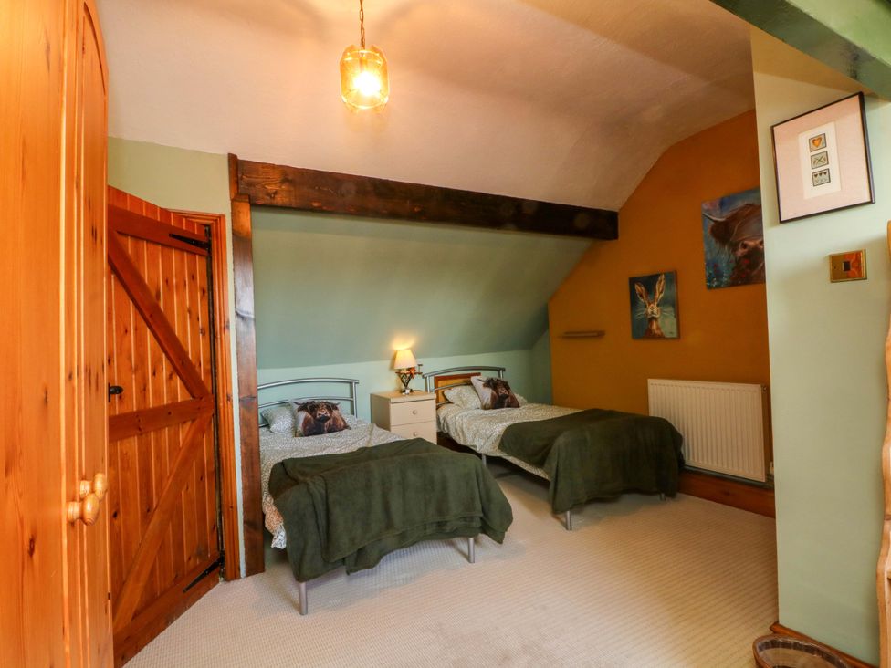 A bedroom with two beds and a wooden door at Pineapple Cottage in 
