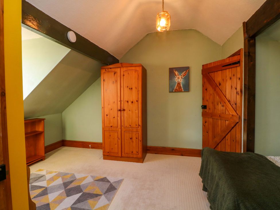 A bedroom with a wardrobe and shelf at Pineapple Cottage
