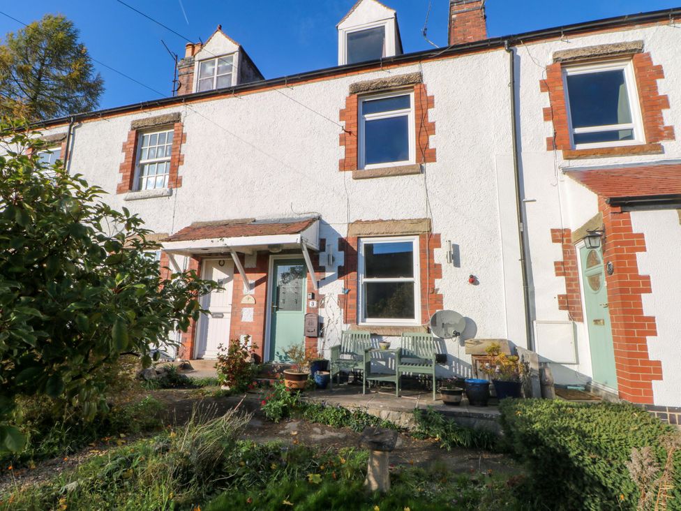 An outdoor view of a house facade with plants and patio at Pineapple Cottage